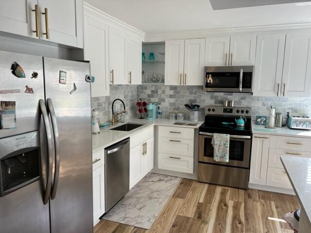 kitchen with sink, white cabinetry, tasteful backsplash, light hardwood / wood-style flooring, and appliances with stainless steel finishes