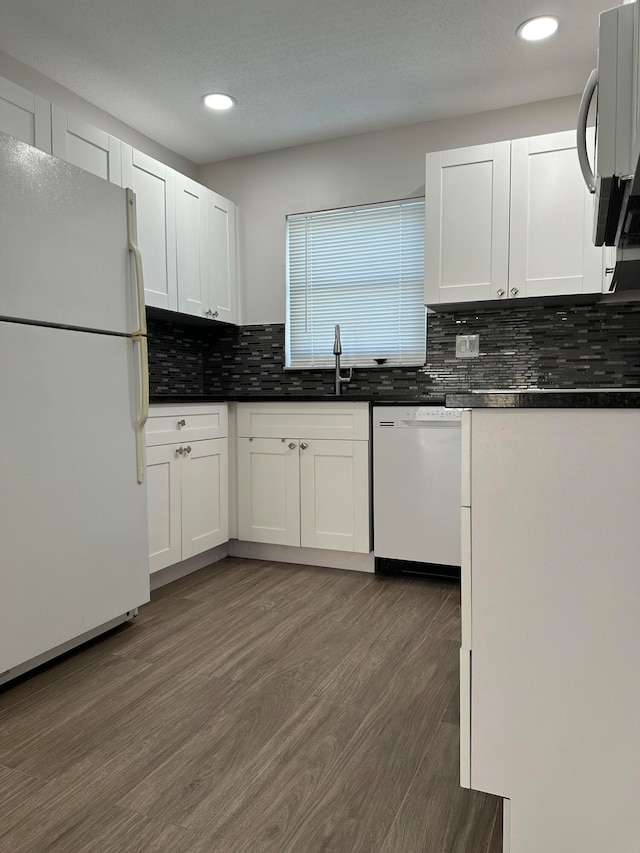 kitchen with white cabinets, white appliances, dark hardwood / wood-style floors, and tasteful backsplash