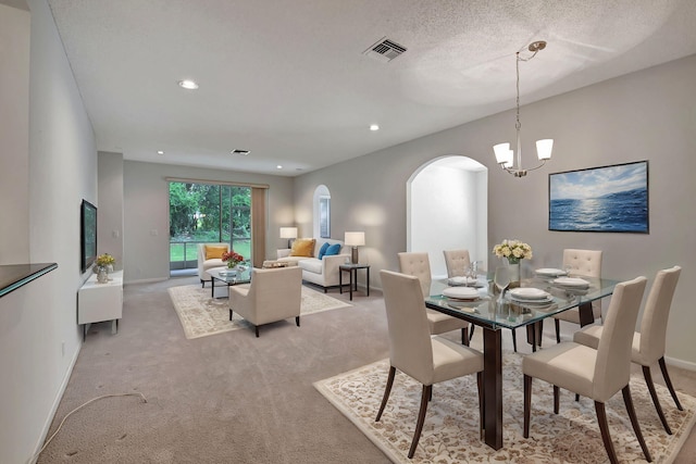 carpeted dining space with a chandelier and a textured ceiling