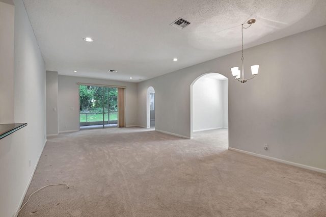 unfurnished living room featuring light carpet, an inviting chandelier, and a textured ceiling