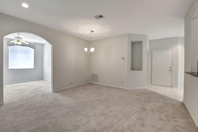 carpeted spare room with ceiling fan with notable chandelier and a textured ceiling