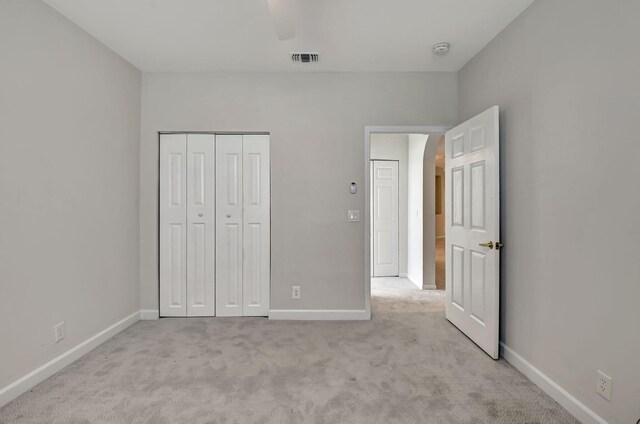 unfurnished bedroom featuring a closet, light carpet, and ceiling fan