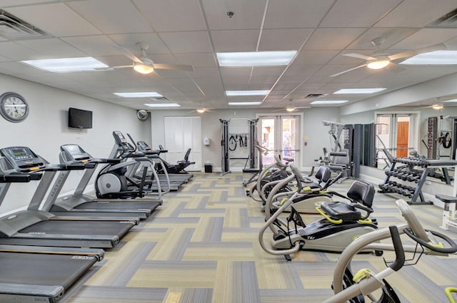 exercise room featuring ceiling fan, a paneled ceiling, and light colored carpet