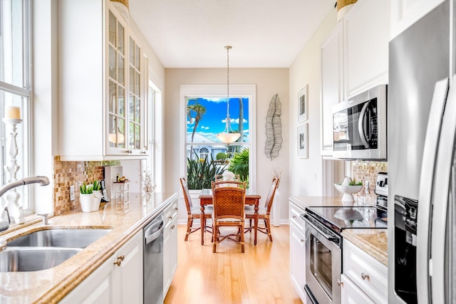 kitchen featuring appliances with stainless steel finishes, hanging light fixtures, sink, and white cabinetry