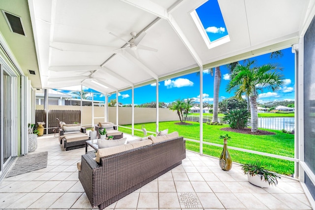 sunroom featuring vaulted ceiling with skylight, a water view, and ceiling fan