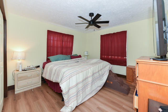 bedroom with light hardwood / wood-style floors, ceiling fan, and a textured ceiling