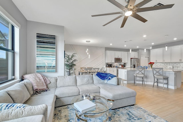 living room with a healthy amount of sunlight, ceiling fan, and light hardwood / wood-style flooring