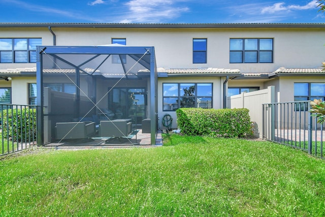 rear view of house with a yard, a patio area, and glass enclosure