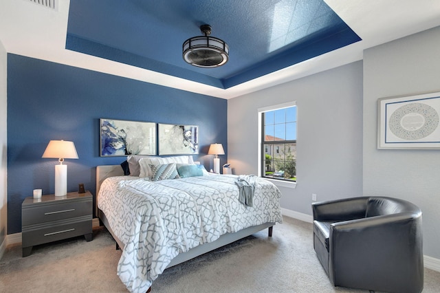 carpeted bedroom featuring a tray ceiling