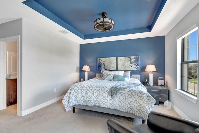 bedroom featuring light carpet and a tray ceiling