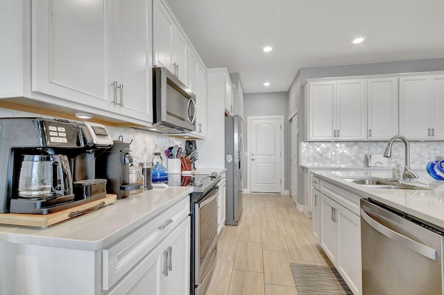 kitchen with decorative backsplash, stainless steel appliances, white cabinetry, and sink