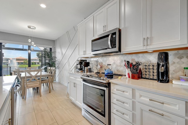 kitchen featuring appliances with stainless steel finishes, hanging light fixtures, white cabinetry, and decorative backsplash