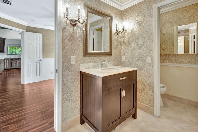 bathroom featuring wood-type flooring, crown molding, toilet, and vanity