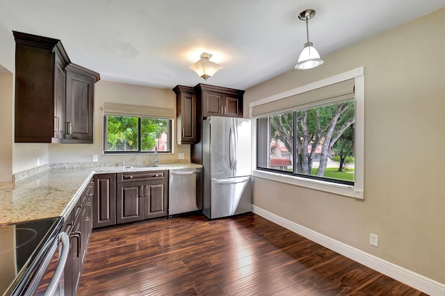 kitchen featuring dark brown cabinets, light stone counters, dark wood-type flooring, hanging light fixtures, and appliances with stainless steel finishes