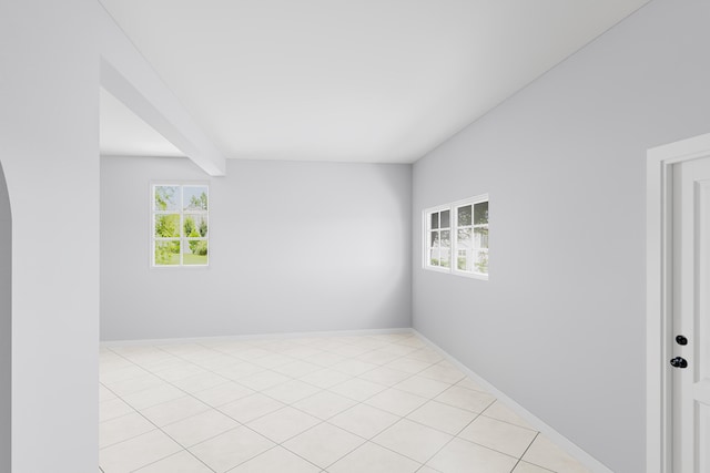 tiled spare room featuring beam ceiling