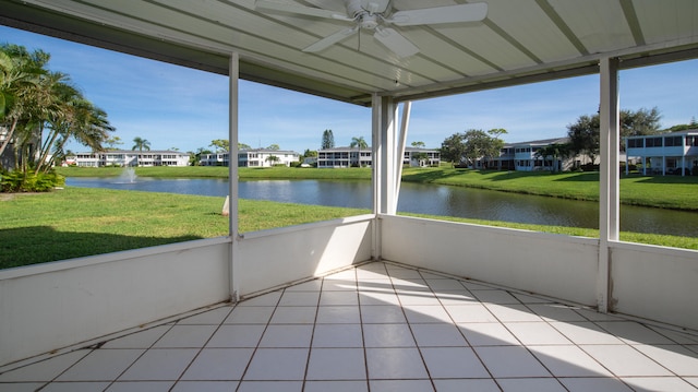 unfurnished sunroom featuring ceiling fan and a water view