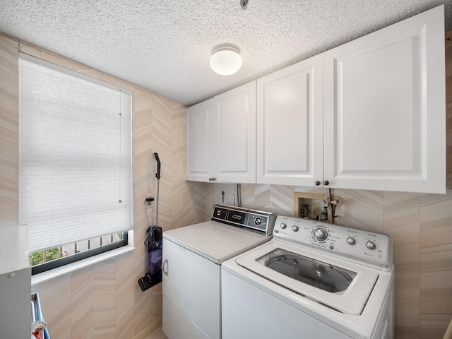 washroom with a textured ceiling, tile walls, cabinets, and separate washer and dryer