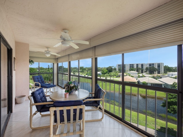 sunroom / solarium featuring a water view and ceiling fan