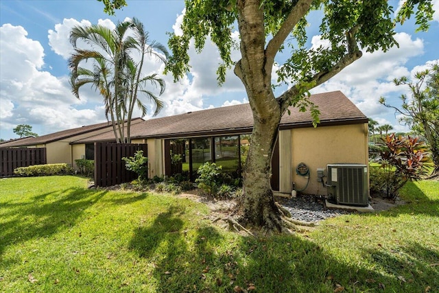 rear view of house with a lawn and central AC unit