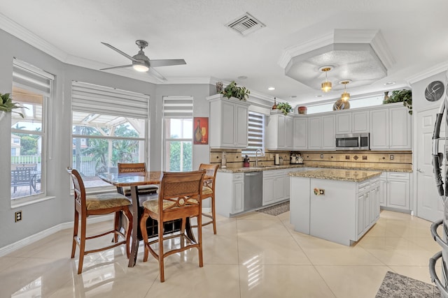 kitchen with decorative backsplash, stainless steel appliances, ornamental molding, and a kitchen island