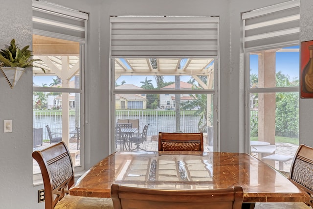 dining area with lofted ceiling with beams and a water view