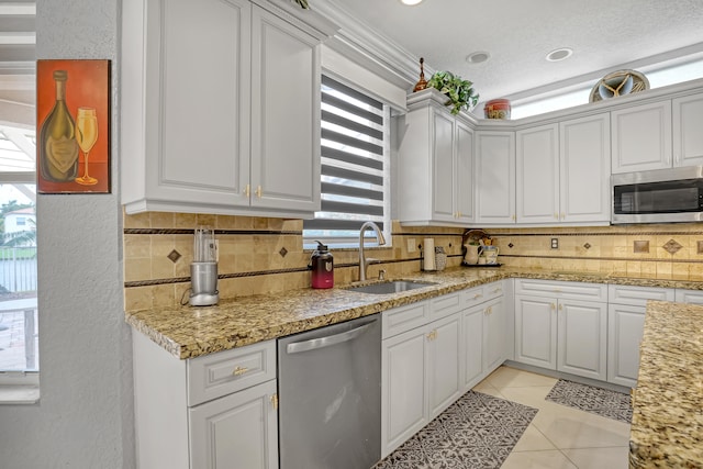 kitchen featuring sink, light tile patterned flooring, stainless steel appliances, white cabinets, and decorative backsplash