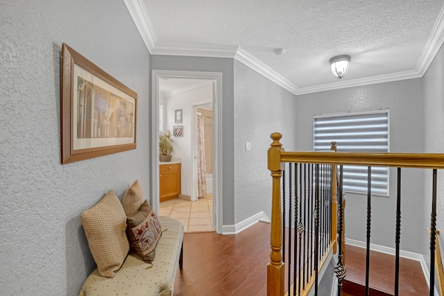 hallway featuring light hardwood / wood-style floors, crown molding, and a textured ceiling