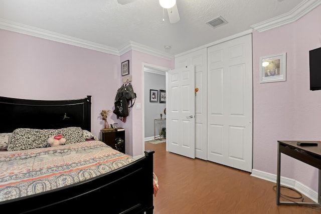 bedroom featuring ceiling fan, a textured ceiling, wood-type flooring, a closet, and crown molding