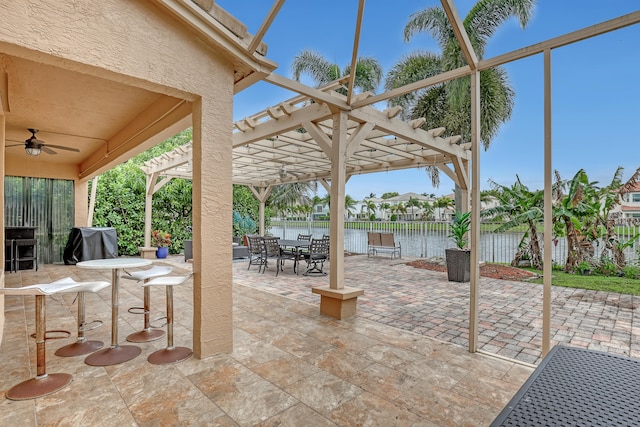 view of patio / terrace with ceiling fan, a water view, and a pergola