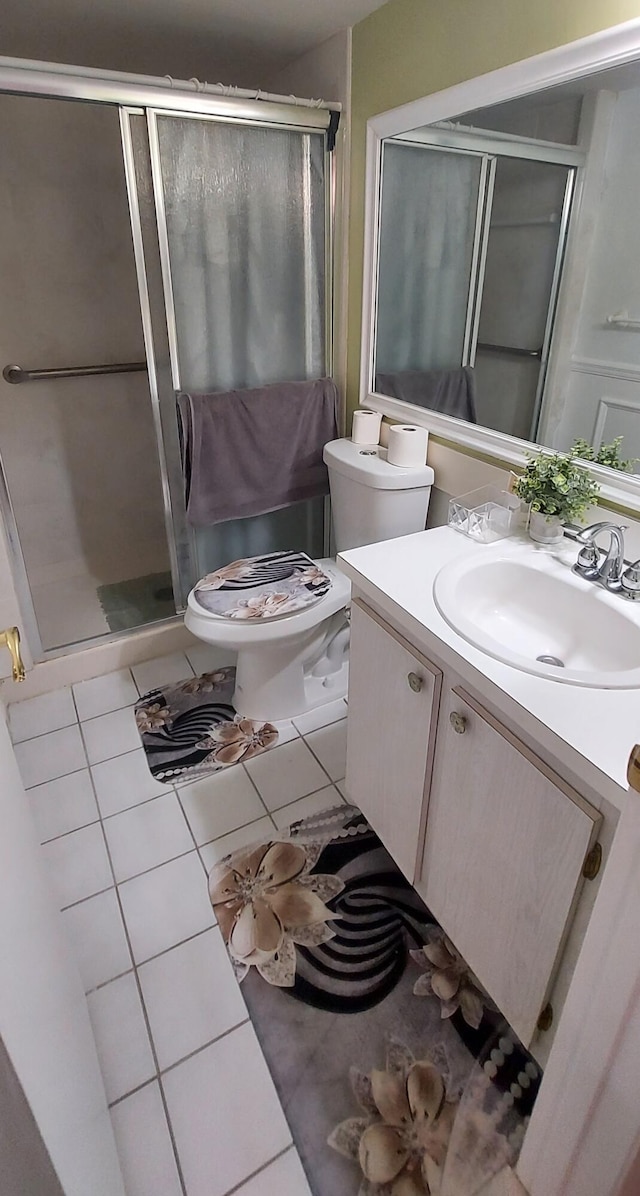 bathroom with tile patterned floors, vanity, a shower with door, and toilet