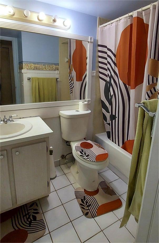 full bathroom featuring shower / bath combination with curtain, vanity, toilet, and tile patterned floors