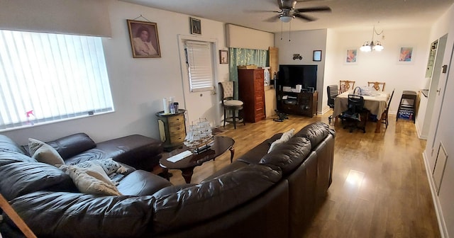 living room with ceiling fan with notable chandelier and hardwood / wood-style flooring