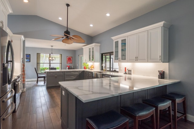 kitchen with lofted ceiling, white cabinets, kitchen peninsula, and decorative light fixtures