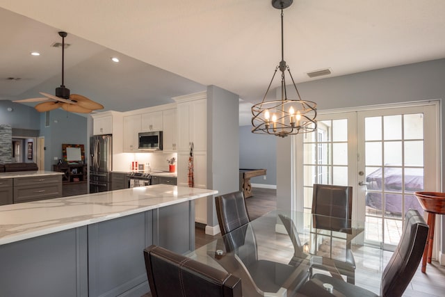 kitchen featuring appliances with stainless steel finishes, white cabinetry, pendant lighting, and a wealth of natural light