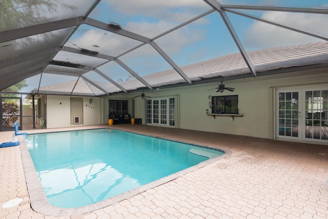 view of pool featuring a patio, glass enclosure, and ceiling fan