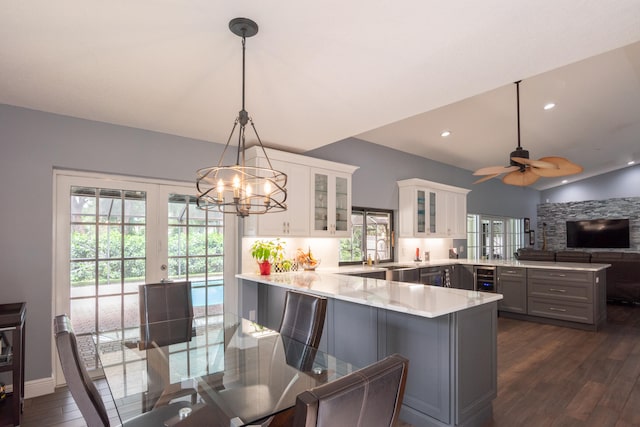 kitchen featuring a kitchen breakfast bar, hanging light fixtures, kitchen peninsula, gray cabinets, and white cabinetry