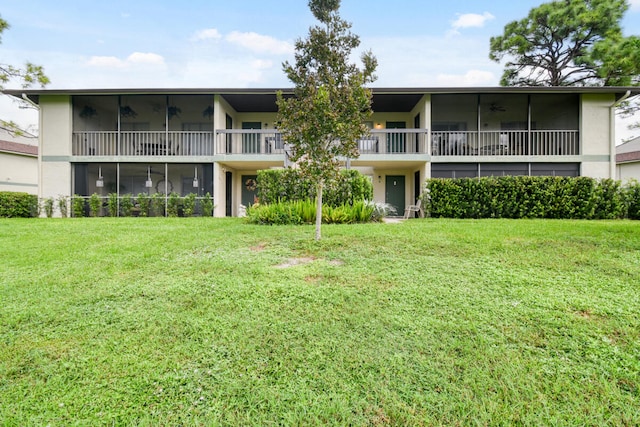 rear view of property with a balcony and a yard