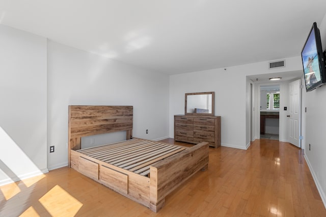 bedroom featuring connected bathroom and light hardwood / wood-style floors