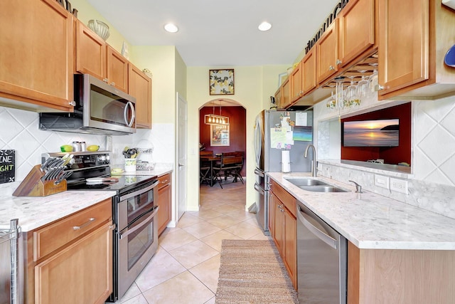 kitchen with light stone counters, light tile patterned flooring, sink, tasteful backsplash, and stainless steel appliances