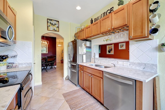 kitchen with backsplash, appliances with stainless steel finishes, light tile patterned floors, and sink