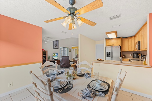 tiled dining space featuring a textured ceiling, sink, and vaulted ceiling