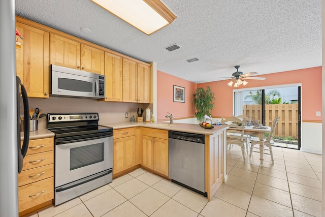 kitchen featuring kitchen peninsula, appliances with stainless steel finishes, a textured ceiling, ceiling fan, and light tile patterned floors