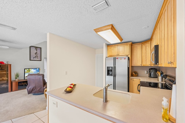 kitchen with sink, light tile patterned floors, a textured ceiling, appliances with stainless steel finishes, and kitchen peninsula