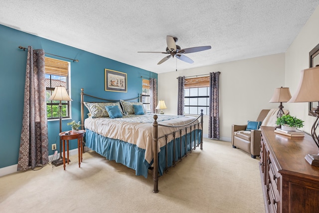 bedroom featuring ceiling fan, light colored carpet, and a textured ceiling