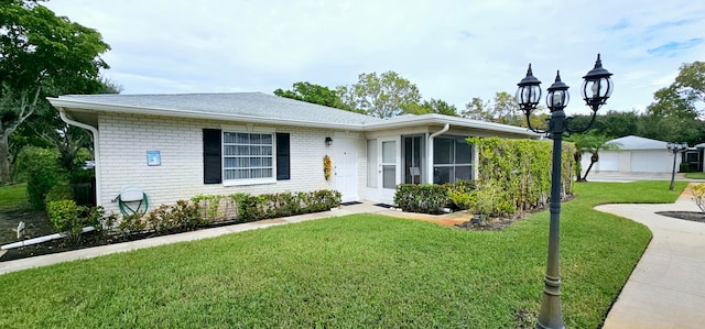 single story home with a front yard, a garage, and an outbuilding