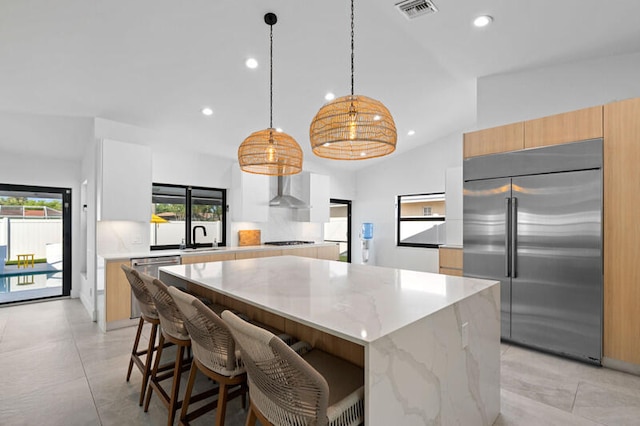 kitchen with a center island, a healthy amount of sunlight, appliances with stainless steel finishes, and decorative light fixtures