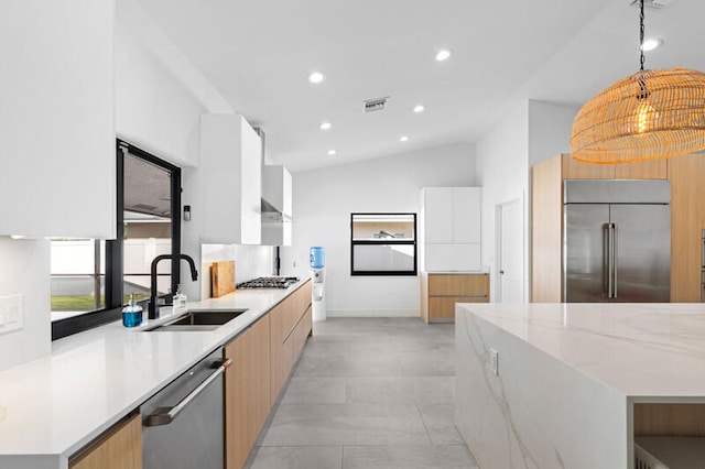 kitchen with appliances with stainless steel finishes, sink, hanging light fixtures, lofted ceiling, and white cabinets