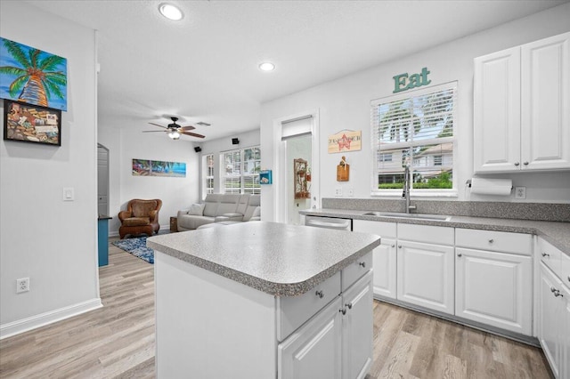 kitchen featuring light hardwood / wood-style flooring, white cabinets, a kitchen island, and sink