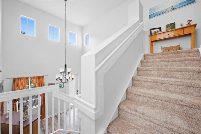 stairway with plenty of natural light and an inviting chandelier