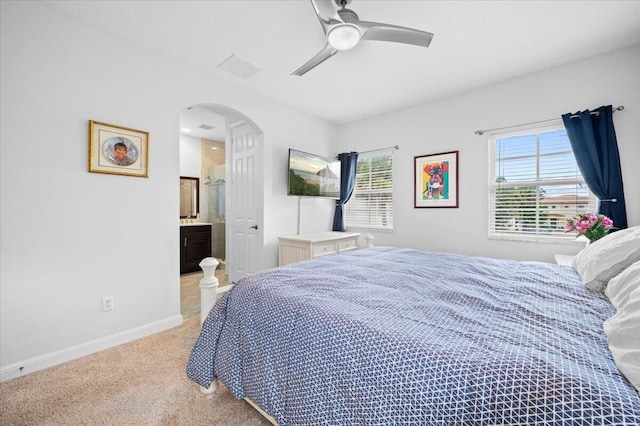 bedroom with light colored carpet, ensuite bathroom, and ceiling fan